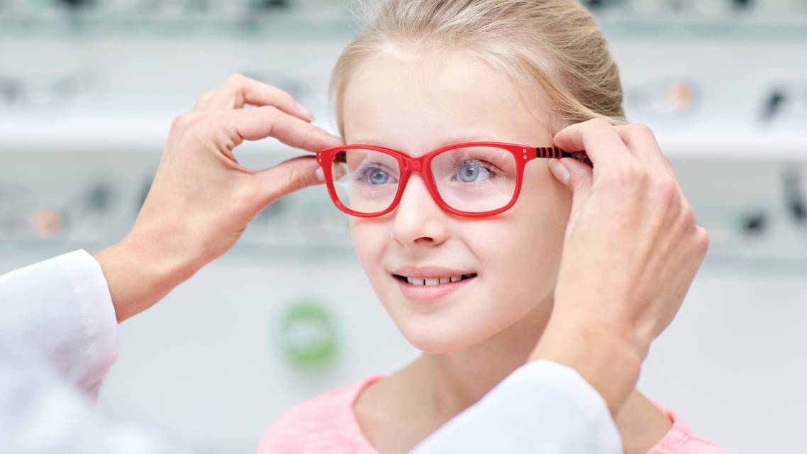 Little girl trying on a pair of red glasses